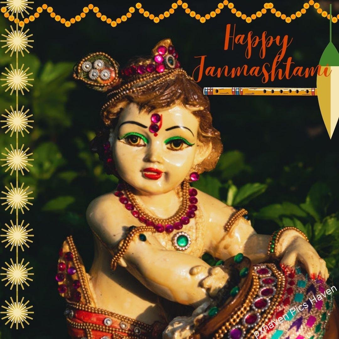 Beautiful Baal Gopal in yellow color dress with laddoo and flute and peacock feather ready for Janmashtami eating Makhan. Happy Janmashtami.